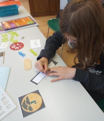 enfant dessine sur un modèle papier